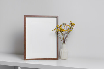 Blank frame mockup in white minimalistic interior with dry flowers in vase