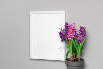 Blank frame mockup with hyacinth flowers over grey wall