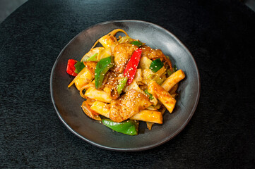 Korean Tteokbokki, Korean spicy stir-fried rice cakes Tteok-bokki with vegetables on black table background