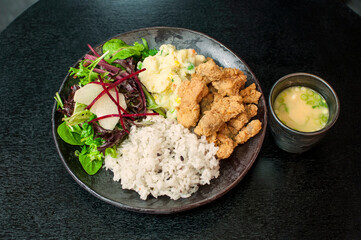 Korean Fried Chicken Dosirak, Korean fried chicken bento box with vegetables on rice on black table background