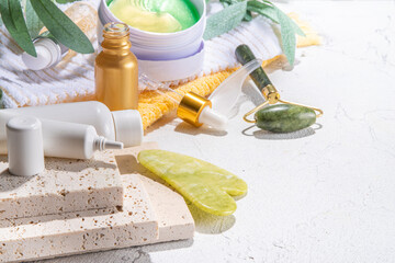 Nature anti-aging cosmetics, therapy massage. Asian beauty skin care. Jade roller, gua sha massager with various organic serum, gel, herbal extract, spa towels. Flatlay on white marble background