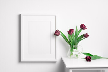 White blank frame mockup on white wall with tulips flowers
