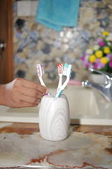  colorful toothbrushes in white mug against a wall 