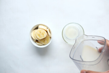 Fototapeta na wymiar top view of slice of banana and glass of milk on table 