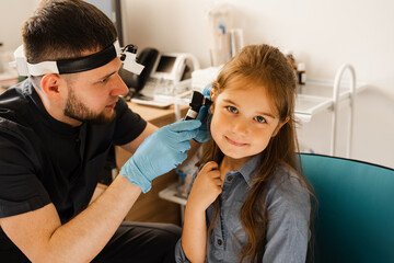 ENT doctor otolaryngologist looks through otoscope the ears of a little girl. Otoscopy. Treatment child ear pain.