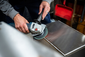 Homme en train de poncer le coin d'une plaque métallique 