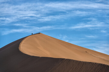 Fototapeta na wymiar Giant sand dune against a blue sky with clouds