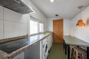 Kitchen of a house with sloping ceilings with green wooden table and pink granite countertop