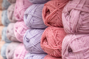 Many multi-colored balls of yarn for knitting on a shelf in a needlework store, close-up, selective focus