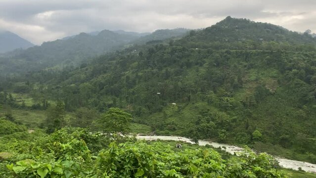 Cinematic picturesque landscape of Bhutan as seen from India with river flowing through the green mountain range.