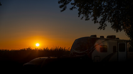 Fototapeta na wymiar Camper trailer camping in sunset light reflecting light and silhouette