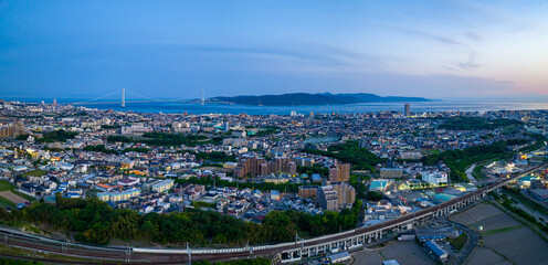 Panoramic aerial view of Akashi City and Awaji Island with bridge in distance at blue hour