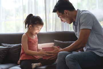 Happy family, little girl and dad with surprise gift boxes in the living room at home, surprise...
