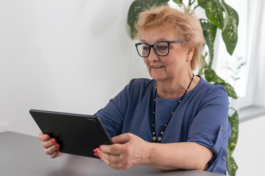 Senior woman making video call from tablet computer at home