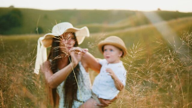 Woman with a hat walks and explores nature carrying her son in her arms