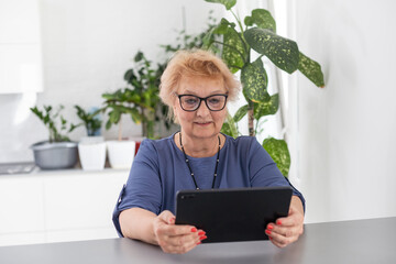 pretty senior woman using tablet computer at home