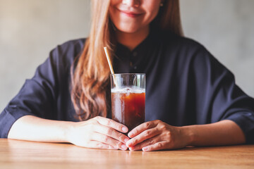 Closeup of a young asian woman holding and drinking iced coffee