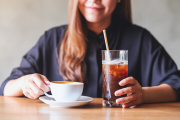 Closeup image of a young woman holding and drinking iced coffee and hot coffee