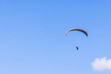 Paraglider flying high up at a blue sky