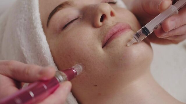 Beautician doing microneedle mesotherapy procedure to a woman's face. Skin care concept. Relaxation concept. Cosmetology dermatology concept.