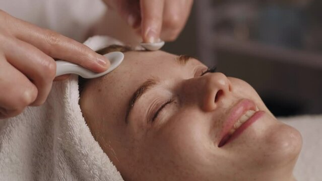 Cosmetologist doing mechanical facial cleansing with uno spoon, removing grease procedure concept. Cosmetic beauty spa salon. Beauty skin. Facial treatment