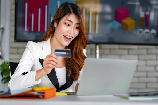 Asian businesswoman using her credit card to shop online at her company office