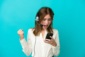 Telemarketer English woman working with a headset isolated on blue background surprised and sending a message