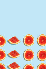 Patterns of slices of juicy grapefruit on a blue background, a beautiful pattern. Top view, full screen. Minimal summer fruits pattern for blog or recipe book. Space for text.