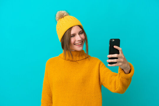 Young English woman wearing winter jacket isolated on blue background making a selfie