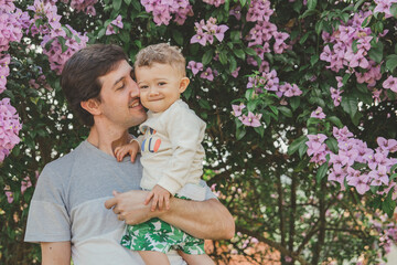 pai com filho bebê no colo em árvore florida