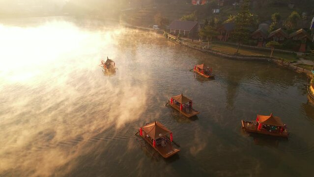Aerial shot of Chinese rowboat at dawn with fog over the Ban Rak Thai Lake and village, Thailand