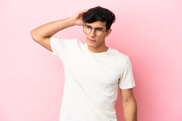 Young Argentinian man isolated on pink background having doubts while scratching head