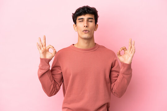 Young Argentinian man isolated on pink background in zen pose