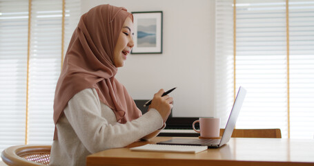 Asia arab people young woman wear hijab headscarf plan study MBA college class note idea data in sale report remote work at home on laptop. Happy advisor lifestyle smile cowork smart workforce job.