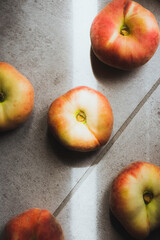 Flat peaches on the floor. Background of food. Sunlight enter the room.