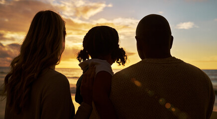 Silhouette closeup of happy family with one child on the beach looking at view at sunset. Two...