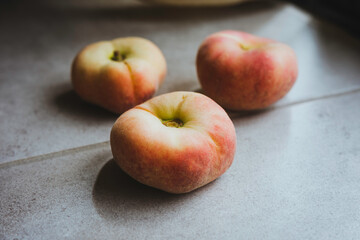 Flat peaches on the floor. Background of food. natural light enter the room.