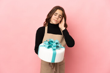 Fototapeta premium Little Pastry chef holding a big cake isolated on pink background with headache