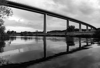 Tall bridge spanning over Ruhr river valley near Essen-Kettwig and Mülheim. German Autobahn A52 from Düsseldorf to Essen on reinforced concrete and steel construction, black and white greyscale.