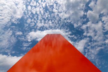 Orange steel bar or pylon reaching to cloudy blue sky on a sunny day in Duisburg Germany near the...