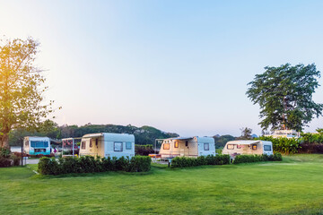 Cozy retro travel trailer Caravan on green grass before sunset near riverside in peaceful countryside. Family vacation travel RV, holiday trip in motorhome. Outdoor and Recreational Vehicles Theme.