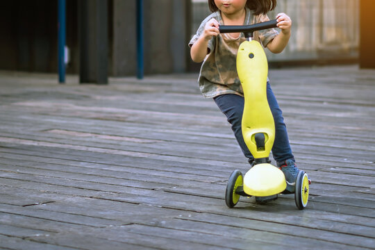 Asian Kid Enjoy Playing And Riding Scooter Without Using Any Safety Gear In Home. Active Lifestyle Of Children In Nature. Happy Little Boy Ride Scooter Without Helmet. Active Sport For Preschool Kid.