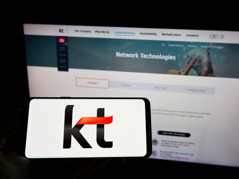 Stuttgart, Germany - 02-11-2022: Person holding cellphone with logo of telecommunications company KT Corporation on screen in front of business web page. Focus on phone display.