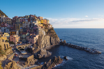 Fototapeta na wymiar Beautiful view of rocky hills and colorful historic buildings of Manarola, tourist attraction and famous place in Liguria, Italy. Hillside over the sea at sunset.