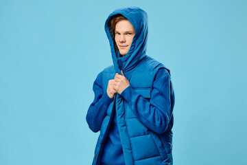 funny handsome guy posing hiding his head in the hood of a warm sleeveless jacket. Cool weather season, horizontal photo for advertising mockup