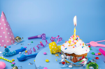 Birthday cake or cupcake with a burning candle on a blue background. Party, birthday or anniversary celebration concept with place for text, copy space
