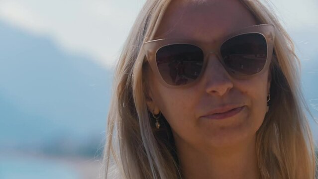 Adult blonde woman takes off her sunglasses