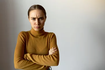 Fotobehang Studio portrait of frowning annoyed angry and offended woman with arms crossed looking at camera isolated on white background with copy space for your content. Body language. People and emotions © Anatoliy Karlyuk