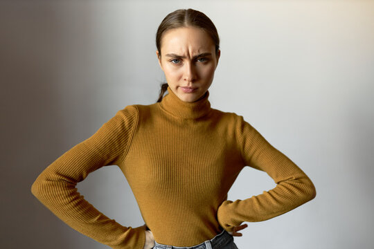 Portrait of frustrated displeased angry woman standing with hands on waist, looking at camera with mad facial expression, frowning with anger, isolated on white. Body language. Negative emotions