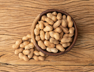 Shelled peanuts on a bowl over wooden table